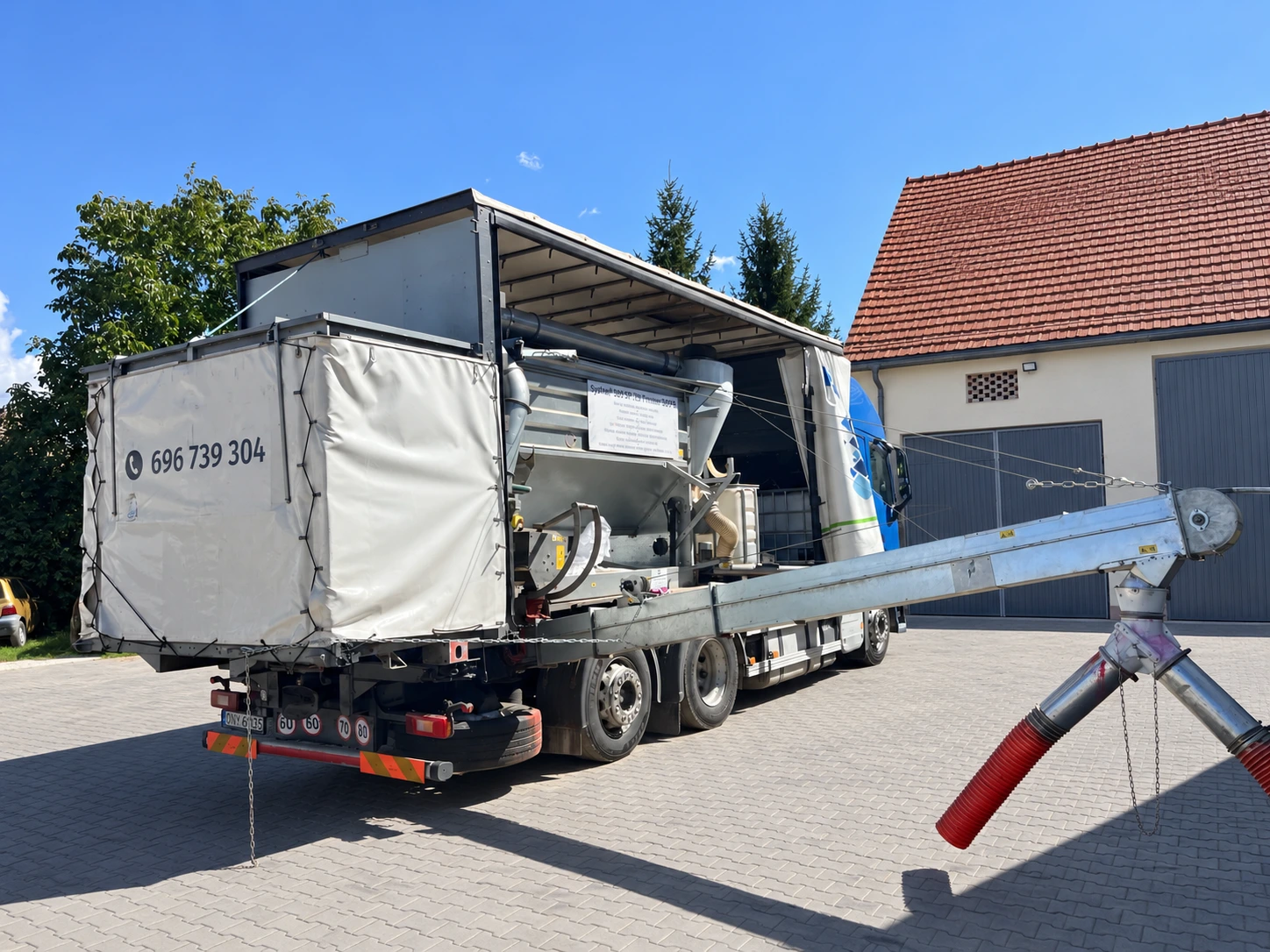 Oryginalne zdjęcie mobilnej zaprawiarki z otwartą zabudową i przenośnikiem w gospodarstwie